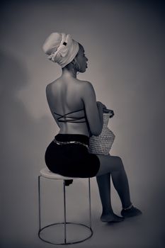Black and white portrait of a woman sitting with stylish attire, in Kaduna, Nigeria.