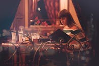 一位女士坐在舒适的餐厅里，享受着优雅的夜晚和柔和的灯光