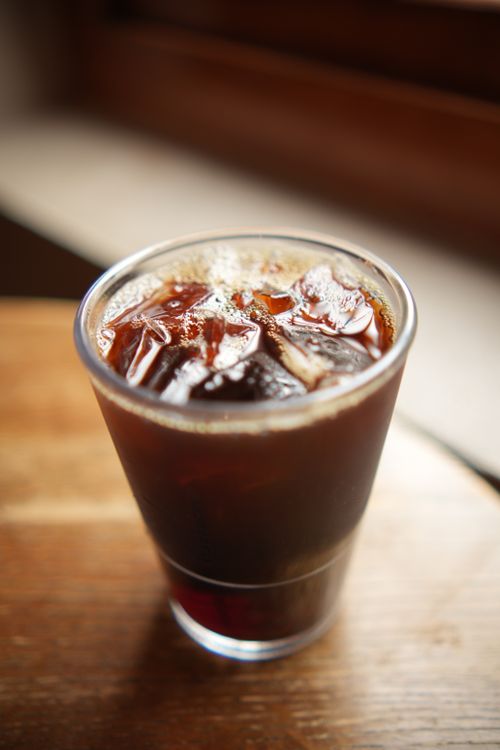Free A glass of iced coffee on a wooden table, captured in natural light, creates a refreshing atmosphere. Stock Photo