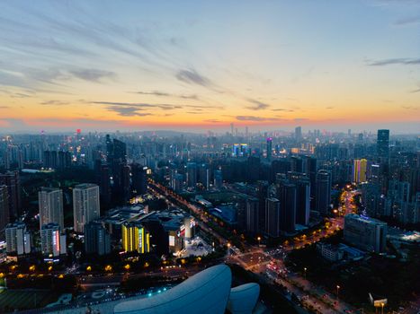 Stunning aerial view of a bustling city skyline at sunset, vibrant lights illuminate the urban landscape.