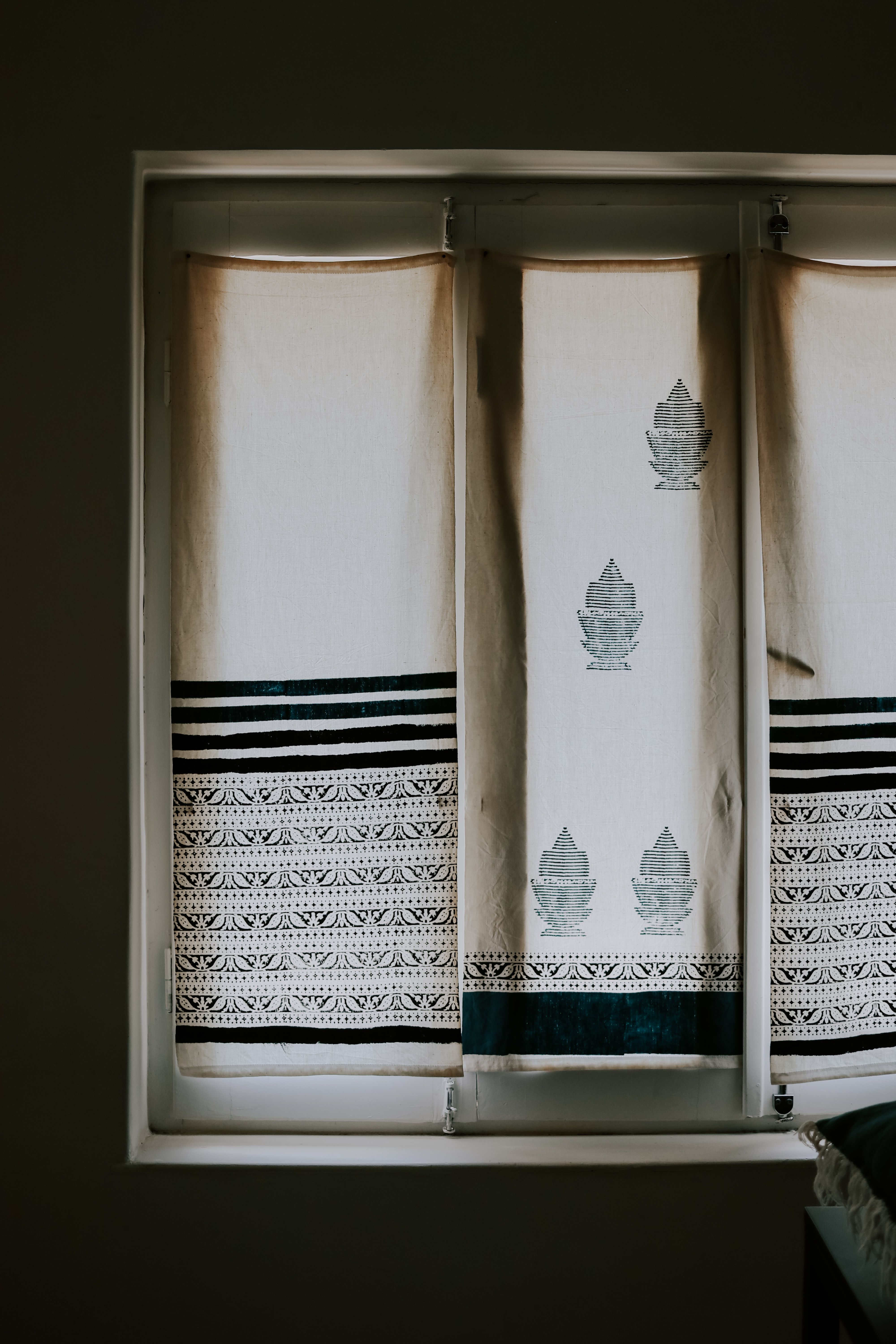 Minimalistic window curtains with intricate ethnic designs filtering soft daylight indoors.