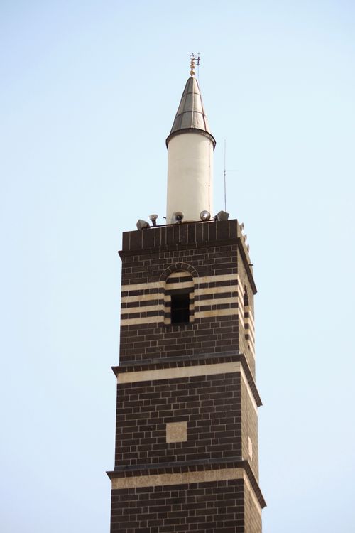 Free A striking brick tower with unique design elements set against a clear blue sky. Stock Photo
