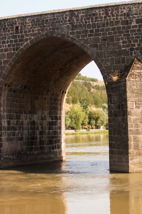 Free A beautiful stone arch bridge spanning a calm river, showcasing historical architecture. Stock Photo