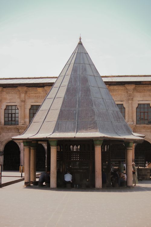 Free A historic courtyard with a traditional gazebo, surrounded by stone architecture under a bright sky. Stock Photo