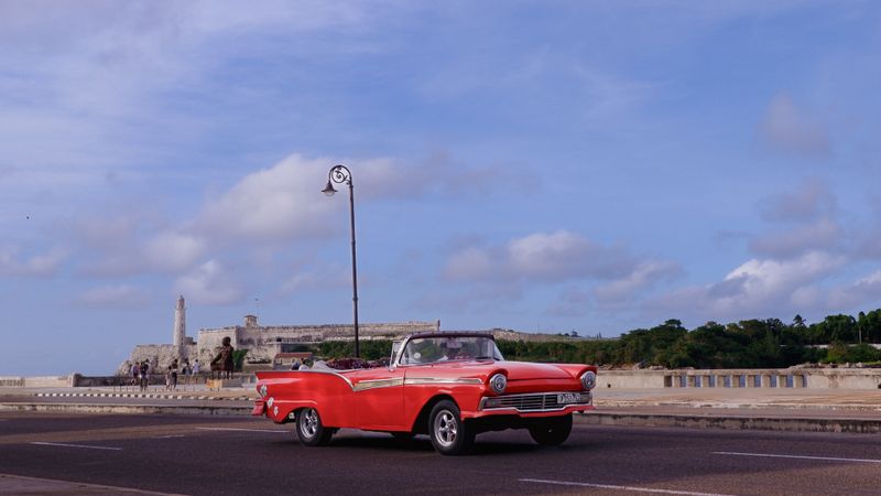 Vintage red convertible car driving on the Malecón in Havana, Cuba