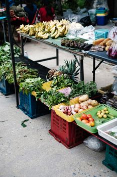 Colorful display of fruits, vegetables, and greens at an outdoor market stall.