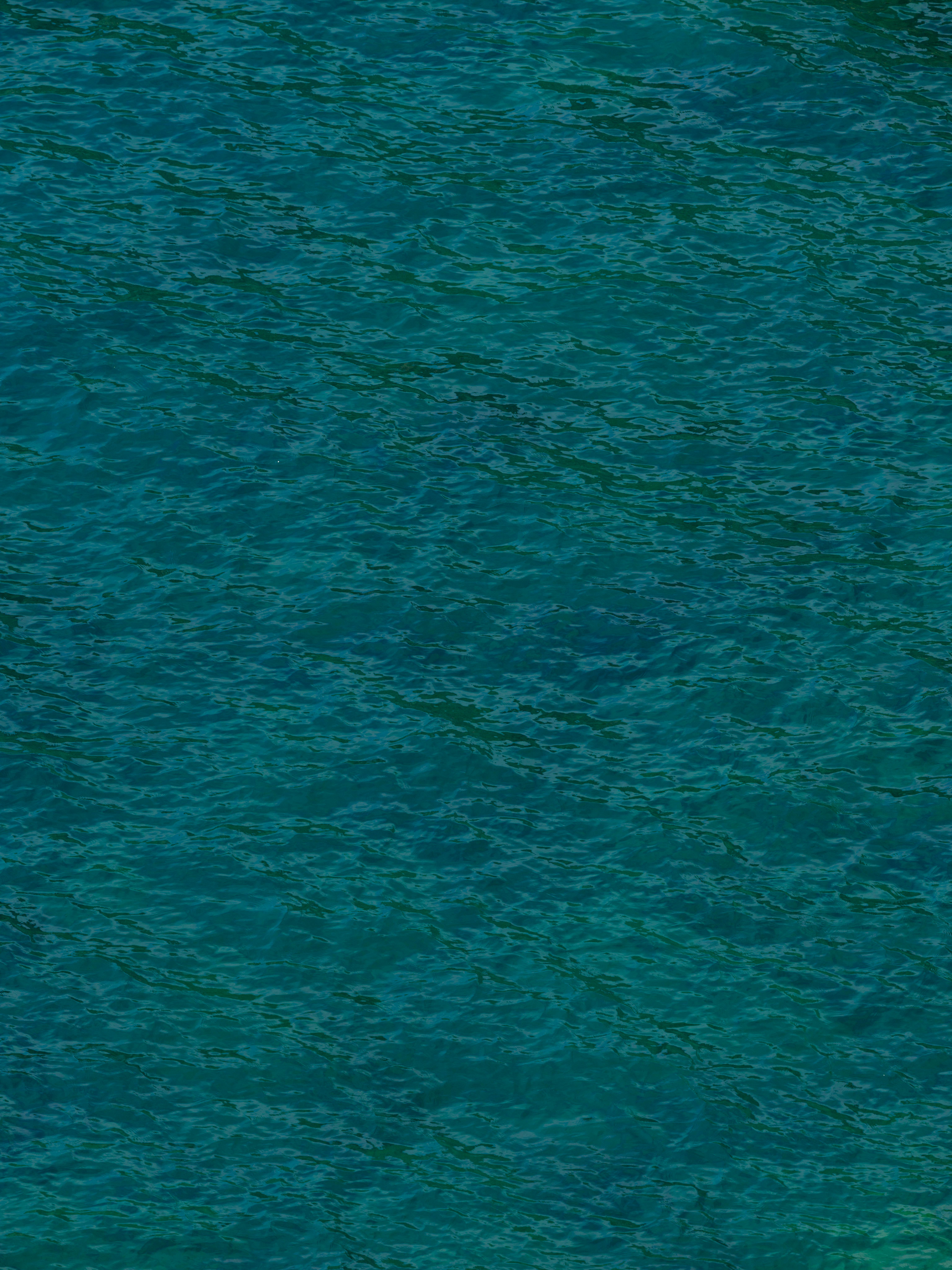 gratis Een levendig bovenaanzicht van het oceaanoppervlak, waarbij de golven rustgevende patronen en texturen creëren. Stockfoto