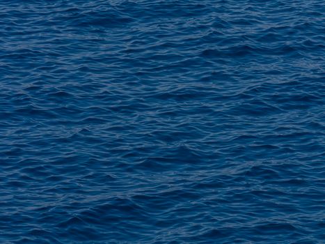 Calm ocean waters with gentle waves reflecting deep blue hues under daylight.