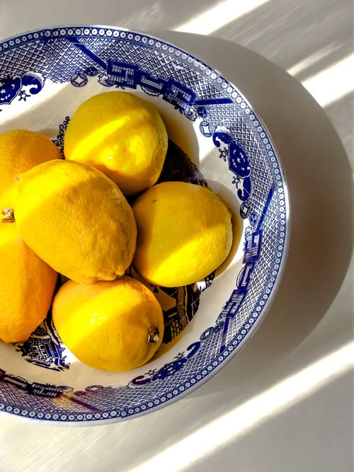 Free Bright yellow lemons in decorative blue porcelain bowl with dramatic lighting. Stock Photo