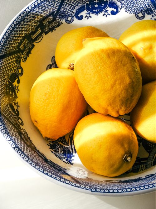 Free Bright yellow lemons in a detailed blue and white bowl. Sunlit and vibrant. Stock Photo