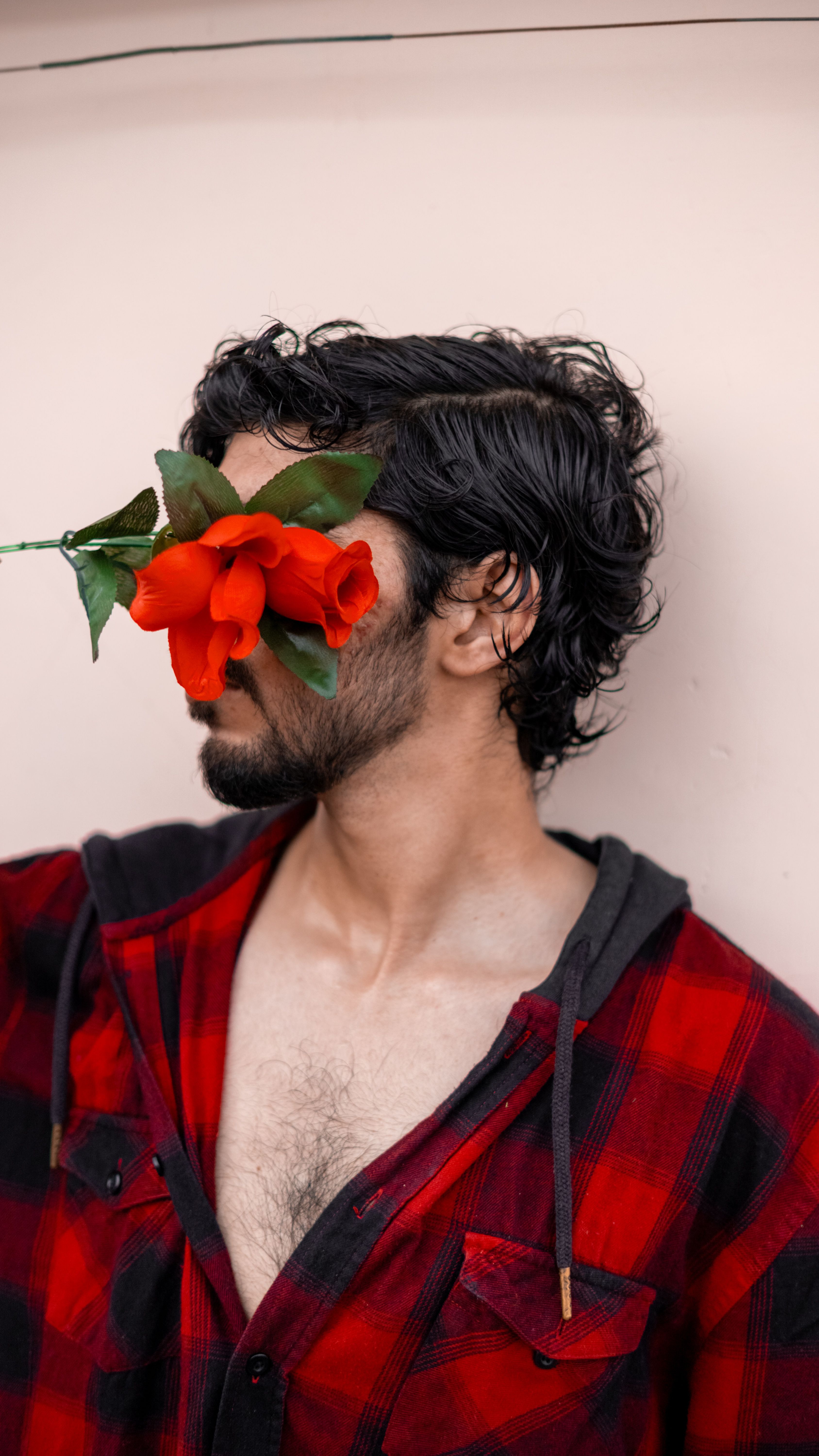 man with red roses covering eyes in plaid shirt