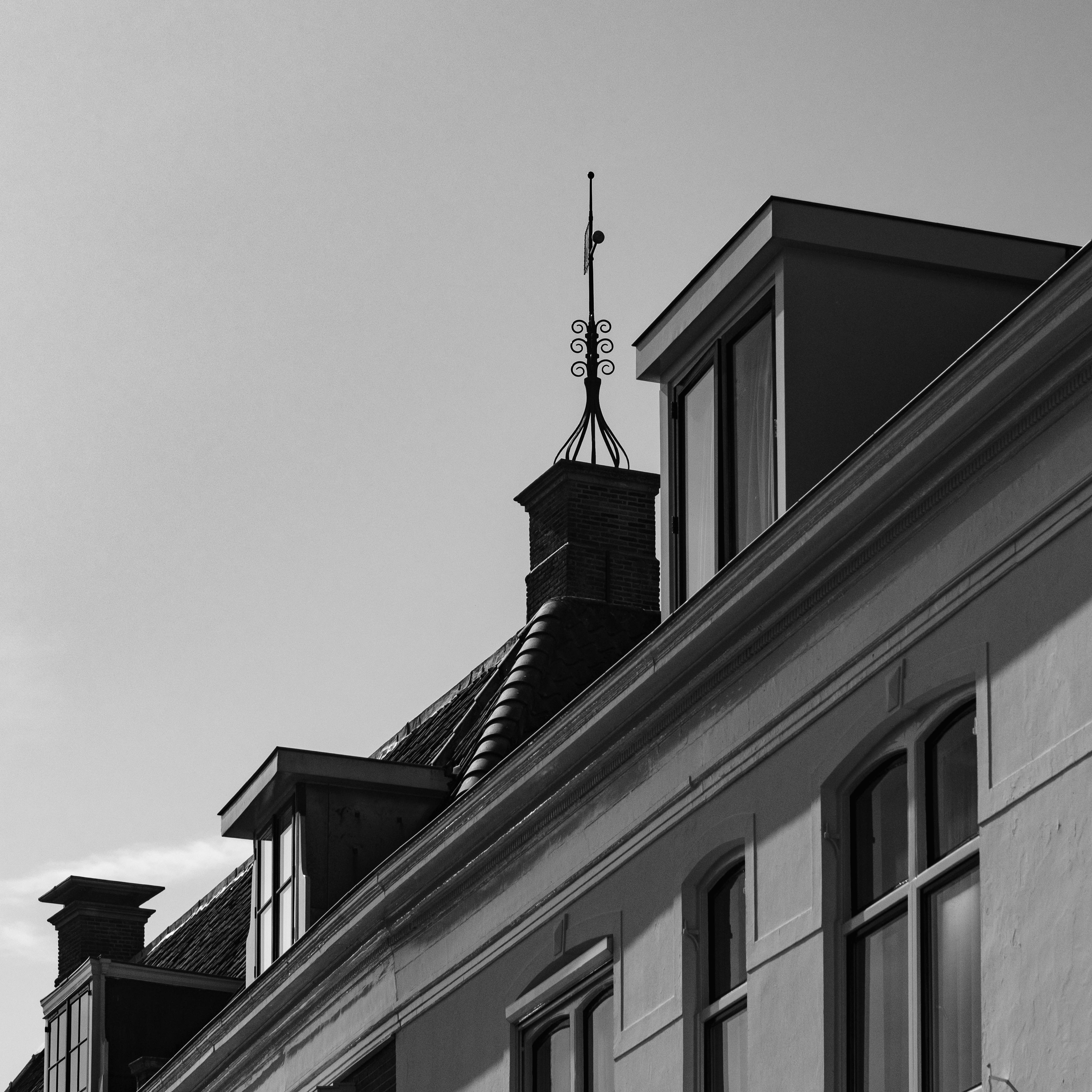 bezplatná Působivý černobílý snímek zobrazující architektonické prvky střechy s vysoce kontrastní oblohou. Základová fotografie