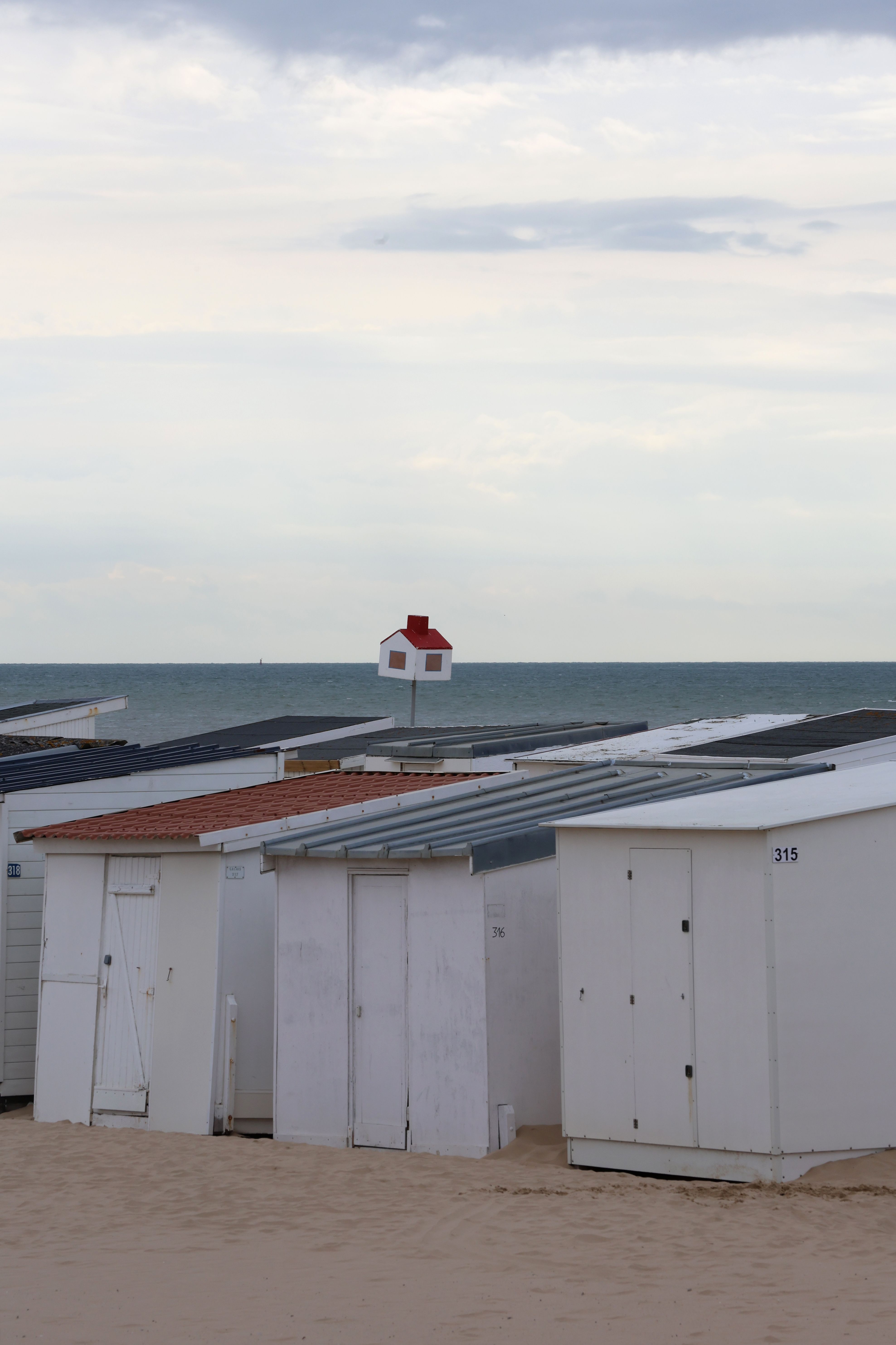 Gratuit Cabines de plage blanches le long de la plage de Calais, avec un poste de secours visible en arrière-plan sur l'océan. Photos