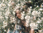 一名女子在白花中摆姿势，具有梦幻般的双重曝光效果，营造出异想天开、空灵的氛围