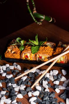 Colorful sushi rolls artfully presented with chopsticks and pebbles.
