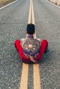 一个纹着卡拉维拉图案的人，坐在荒无人烟的路上，背影