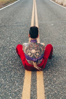 一个纹着卡拉维拉图案的人，坐在荒无人烟的路上，背影