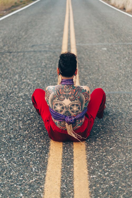 Free Person With Calavera Tattoo on Back Sitting in Middle of Street Stock Photo