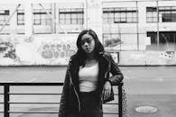 一位身穿黑色皮夹克的迷人女子，在城市背景下时尚地摆出姿势