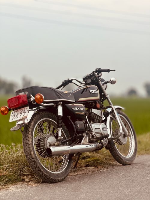 Free A timeless Yamaha RX135 motorcycle parked on a rural road, offering a nostalgic view. Stock Photo