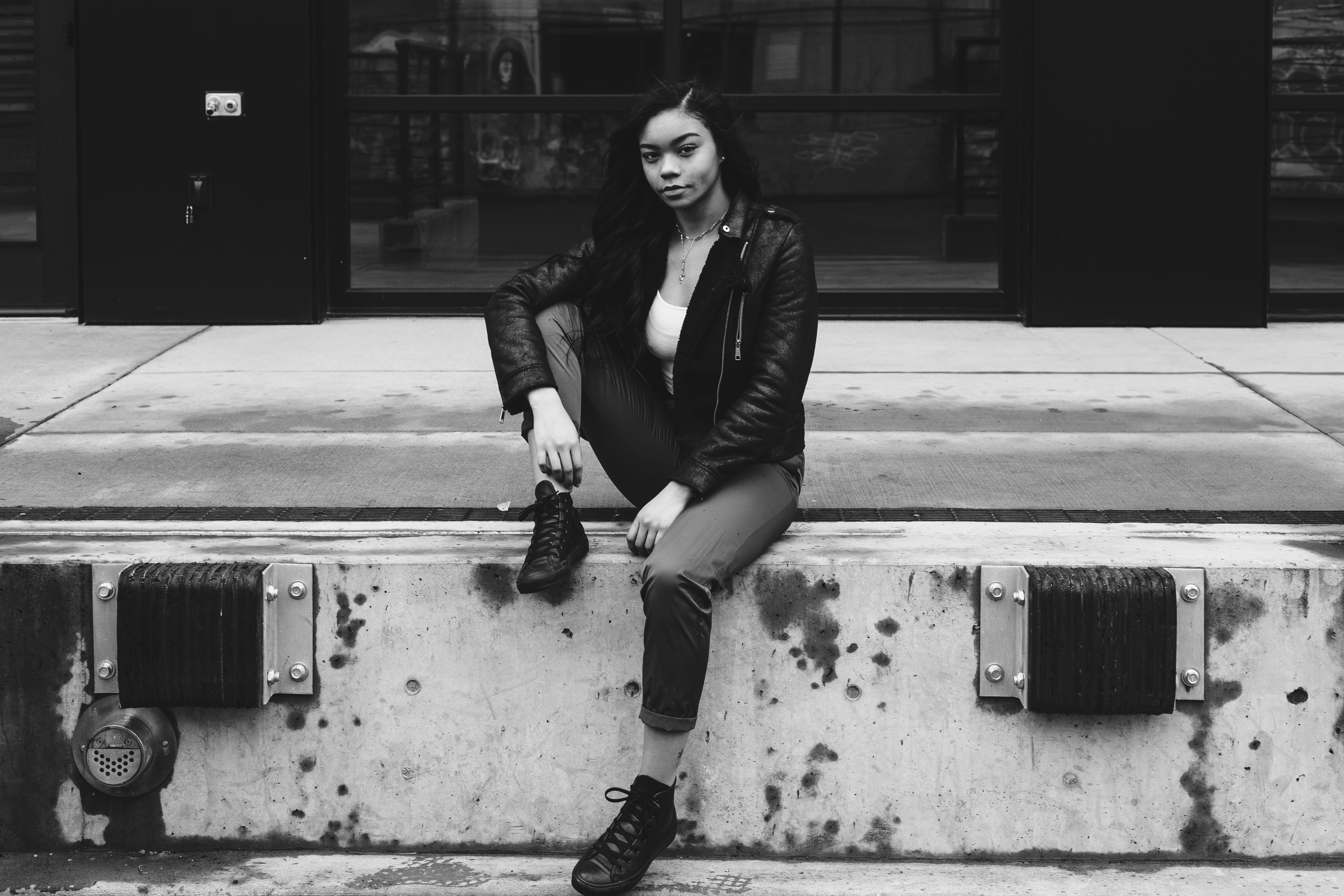 一张时尚的黑白照片中，一位年轻女子在城市环境中摆着姿势