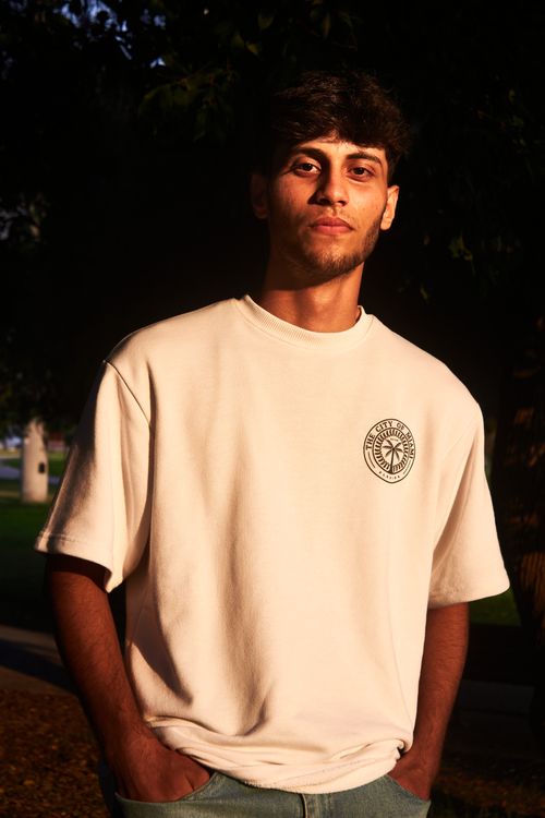 Free Portrait of a young man in a white shirt standing outdoors during golden hour, with dramatic lighting. Stock Photo