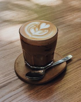 A beautifully crafted flat white coffee with graceful latte art served on a wooden table, exuding warmth and cozy vibes.