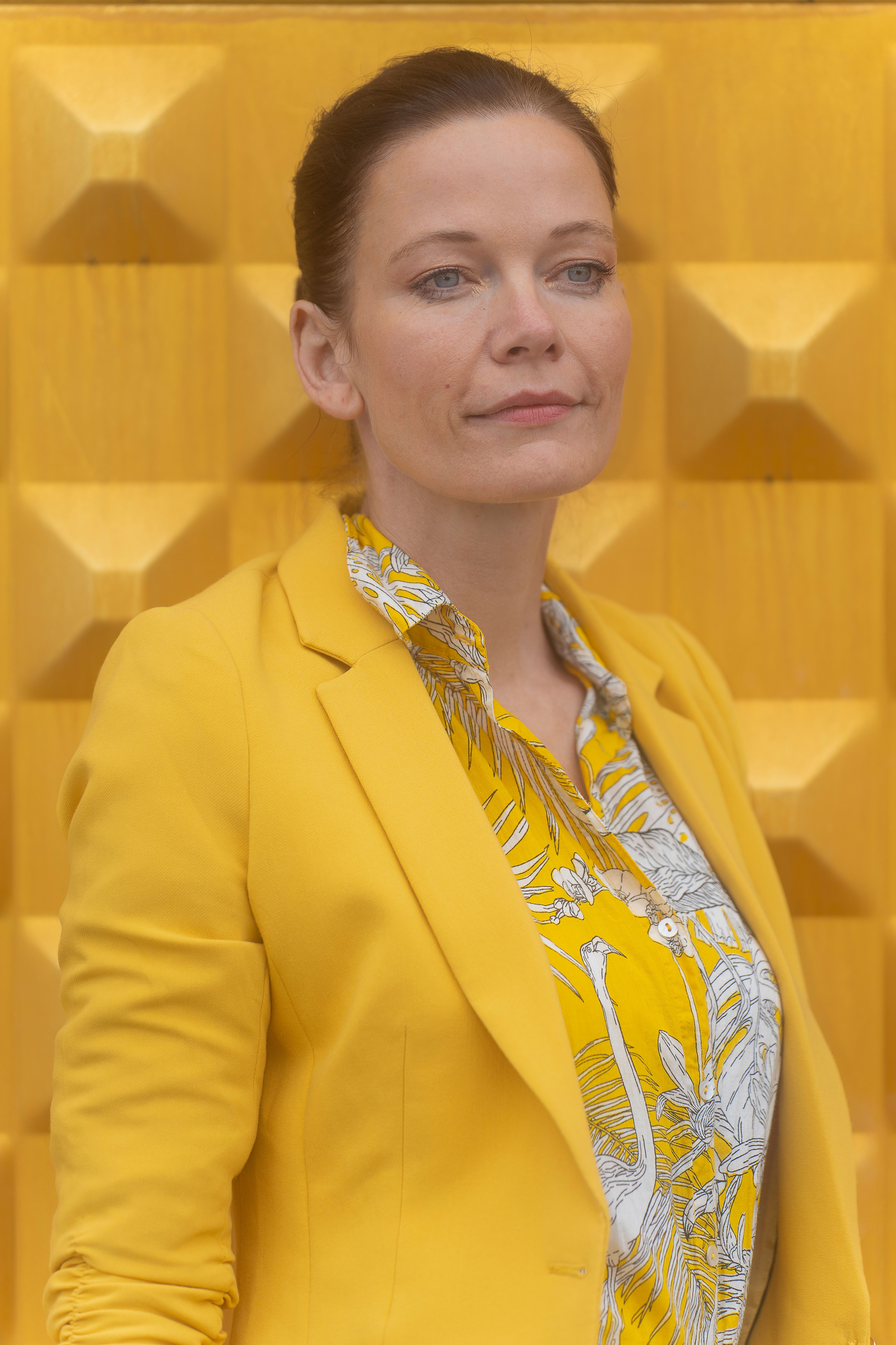 Confident woman in striking yellow outfit against geometric background in Berlin.