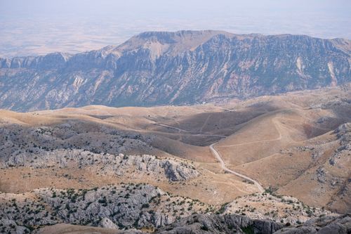 Free A breathtaking view of a rugged mountainous landscape with a clear winding road visible. Stock Photo