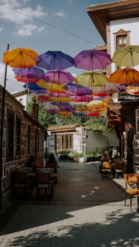 Charming street with vibrant umbrella canopy offering shade in a cozy outdoor café setting.