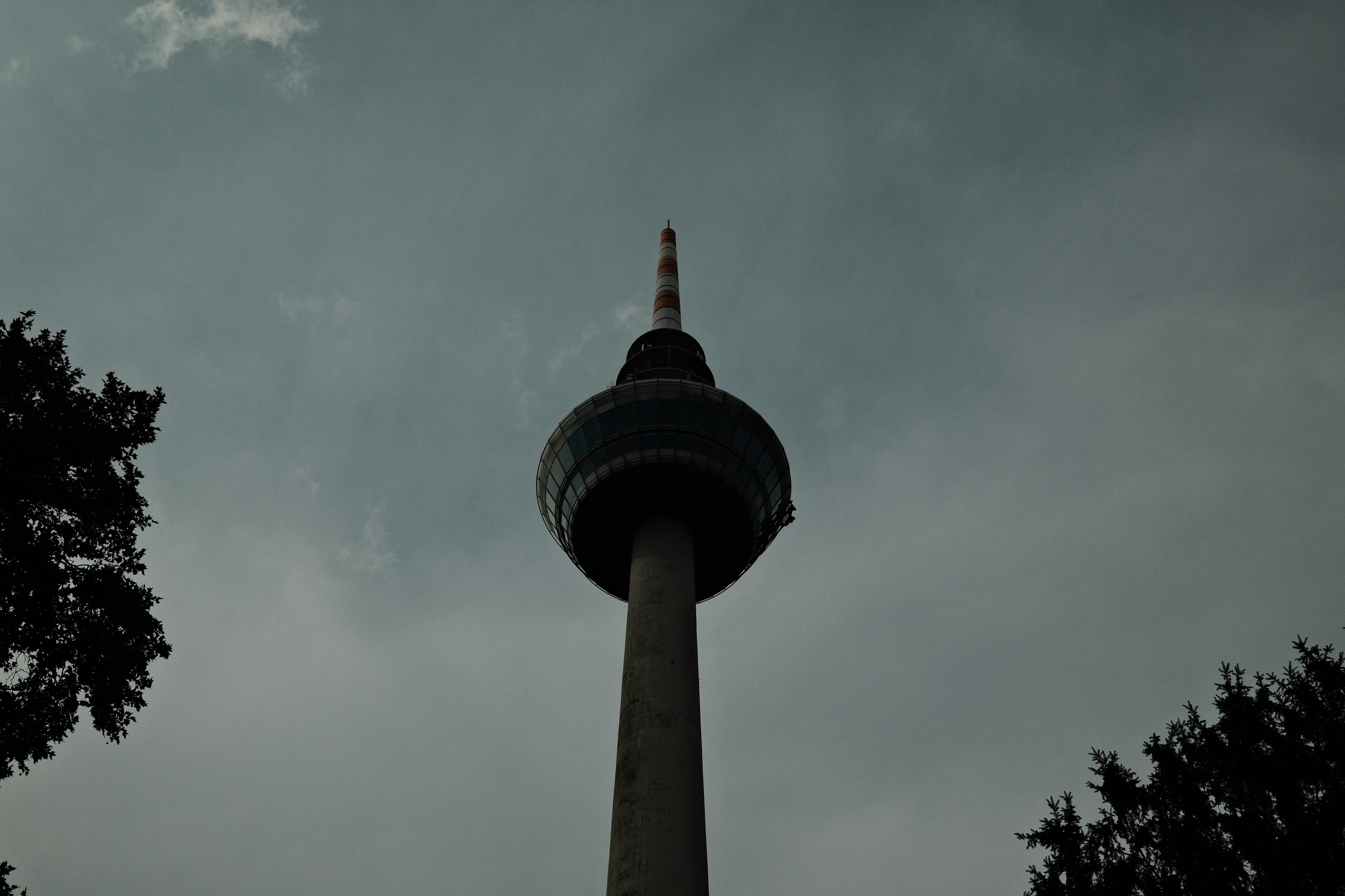 Moody silhouette of a TV tower with cloudy sky, showcasing architectural beauty and atmospheric mood.