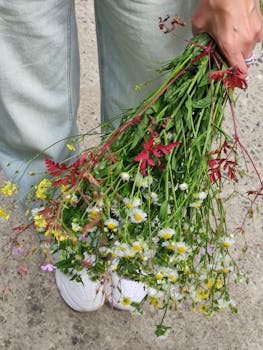 Vibrant bouquet of wildflowers held by person outdoors.
