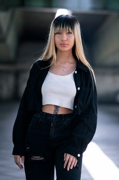 Stylish young woman poses confidently in urban Tehran with edgy street fashion.