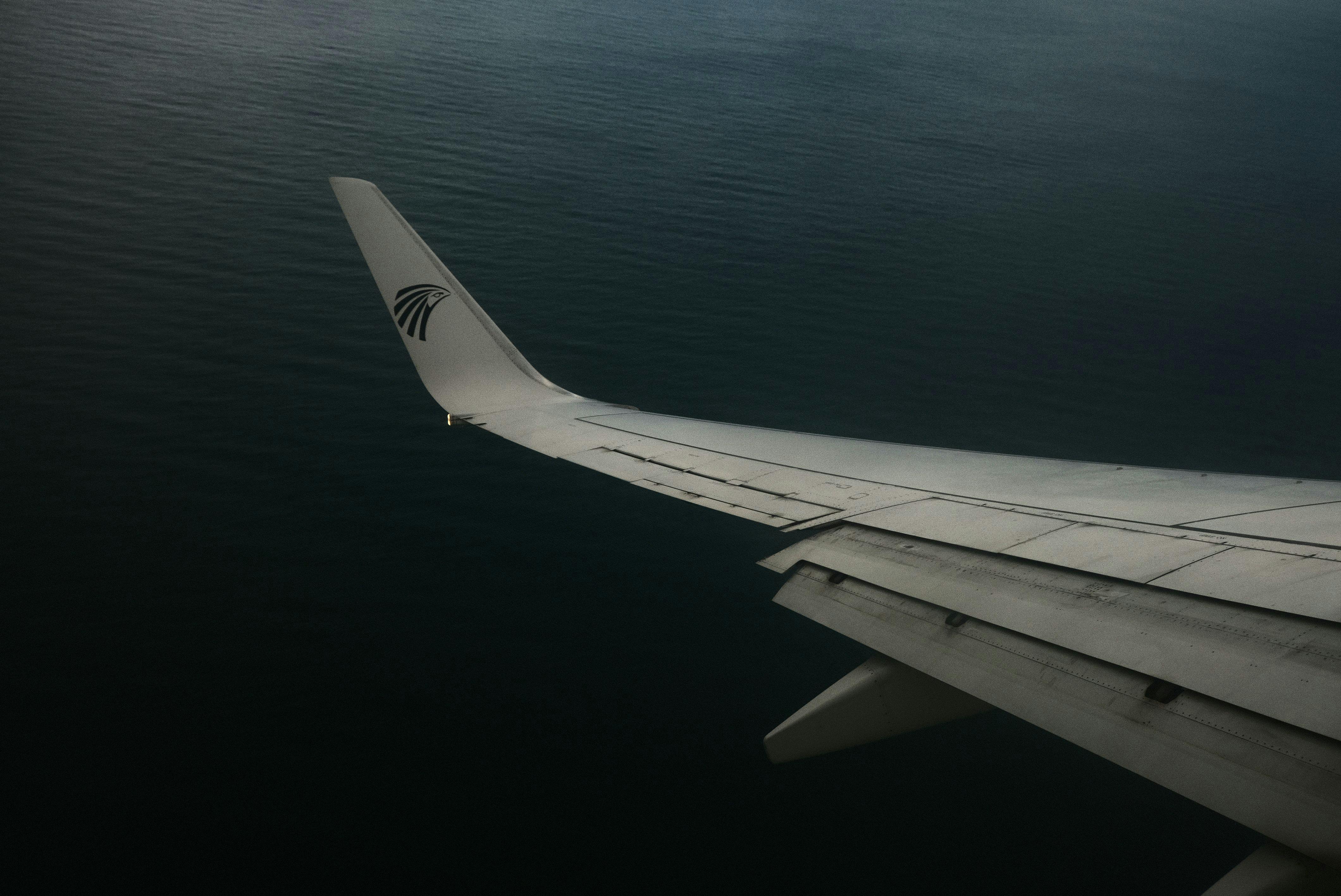 View from airplane window showing aircraft wing over calm ocean waters near Cairo.