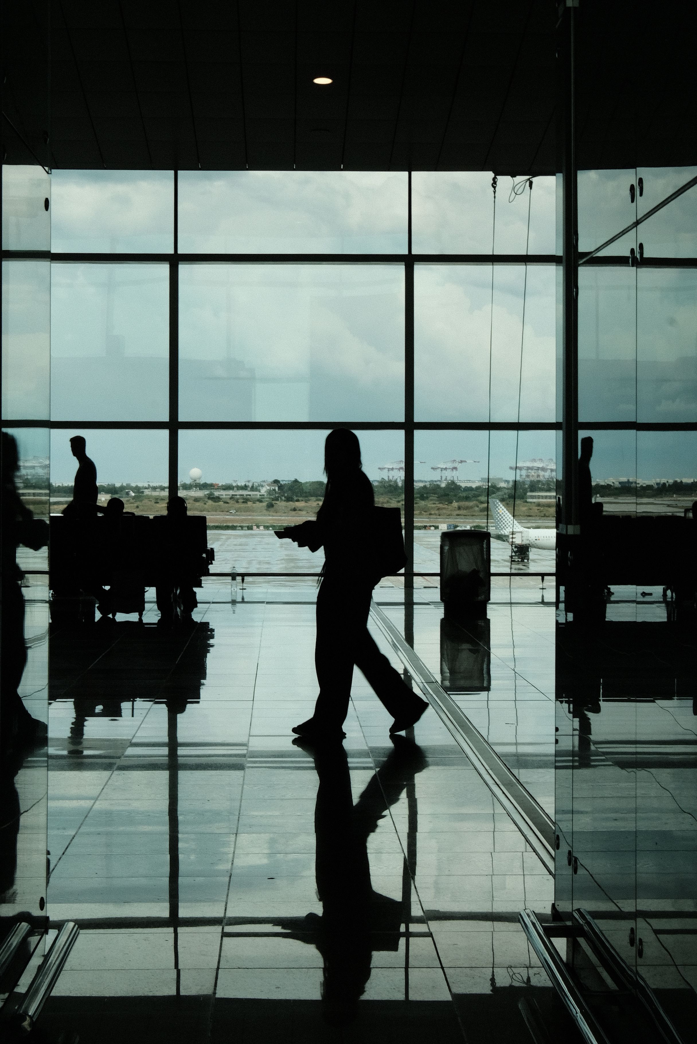 Silhouetted travelers walking through Barcelona airport terminal