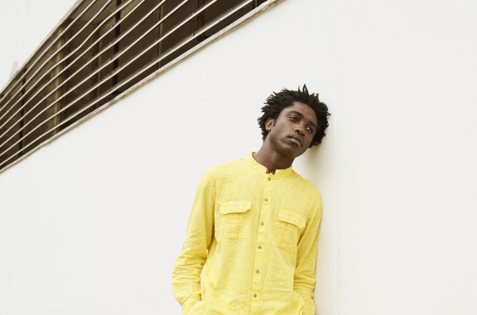 Contemporary portrait of a young man in a vibrant yellow shirt against a modern background.