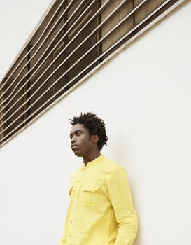 Portrait of a man in a bright yellow shirt against minimal architecture.