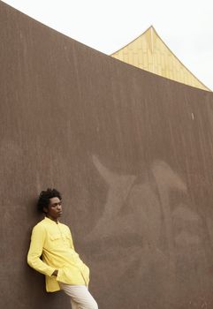 A man in yellow stands against modern architecture in Berlin, combining style and simplicity.