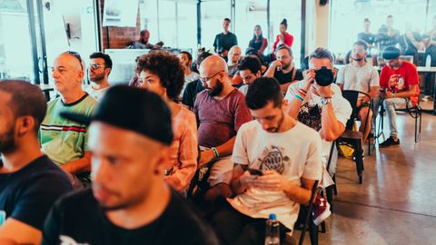 Diverse group of people attending a modern conference, engaged in listening and discussions.