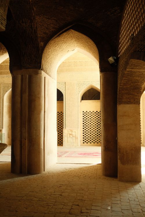 Free Warm-lit view of historic mosque interior in Isfahan, showcasing arches and intricate carvings. Stock Photo
