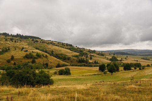 Free Beautiful summer landscape of rolling hills in Косатица, Serbia, under a cloudy sky. Stock Photo