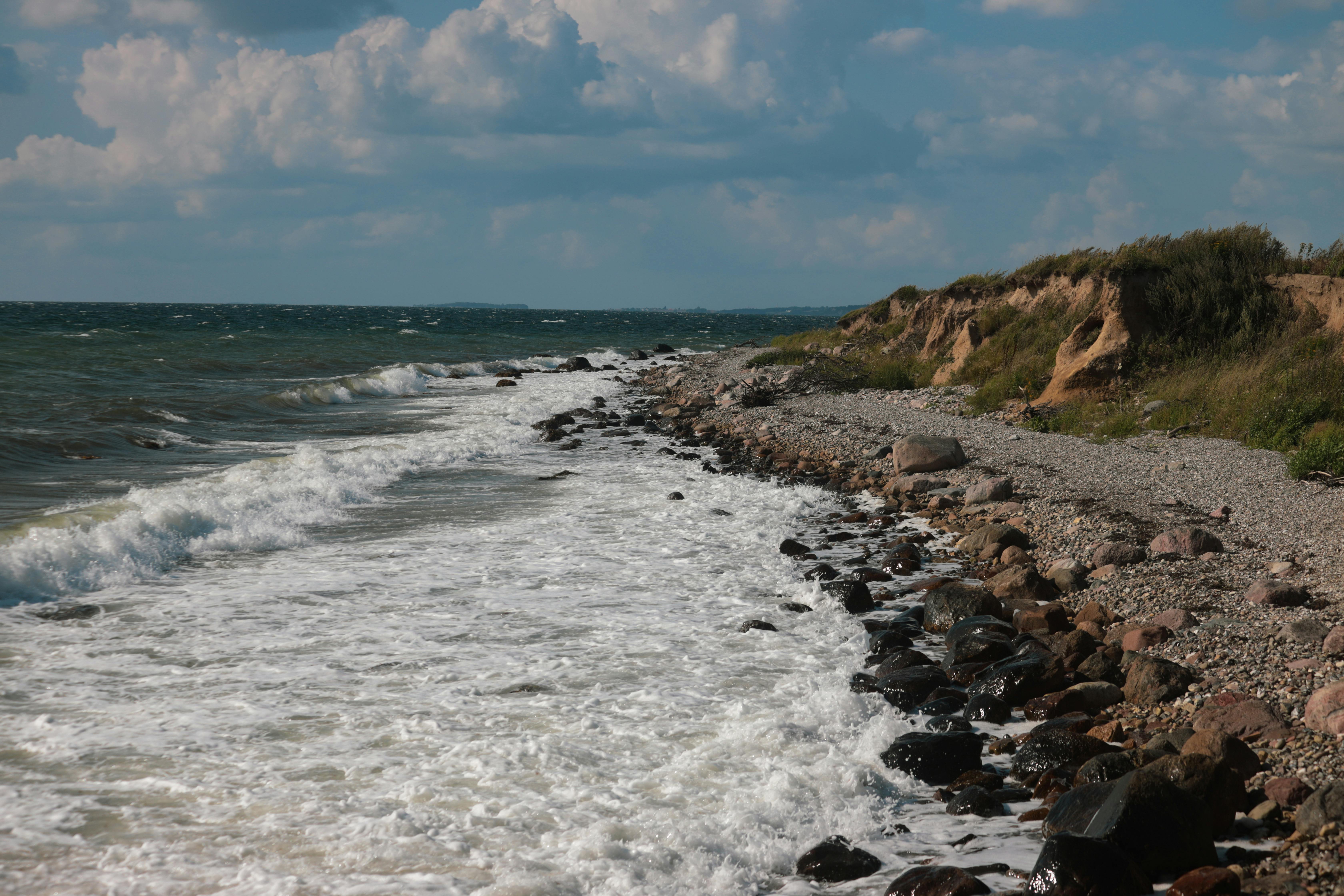 Explore the unspoiled rocky shoreline and waves of Ebberup, Denmark on a summer day.