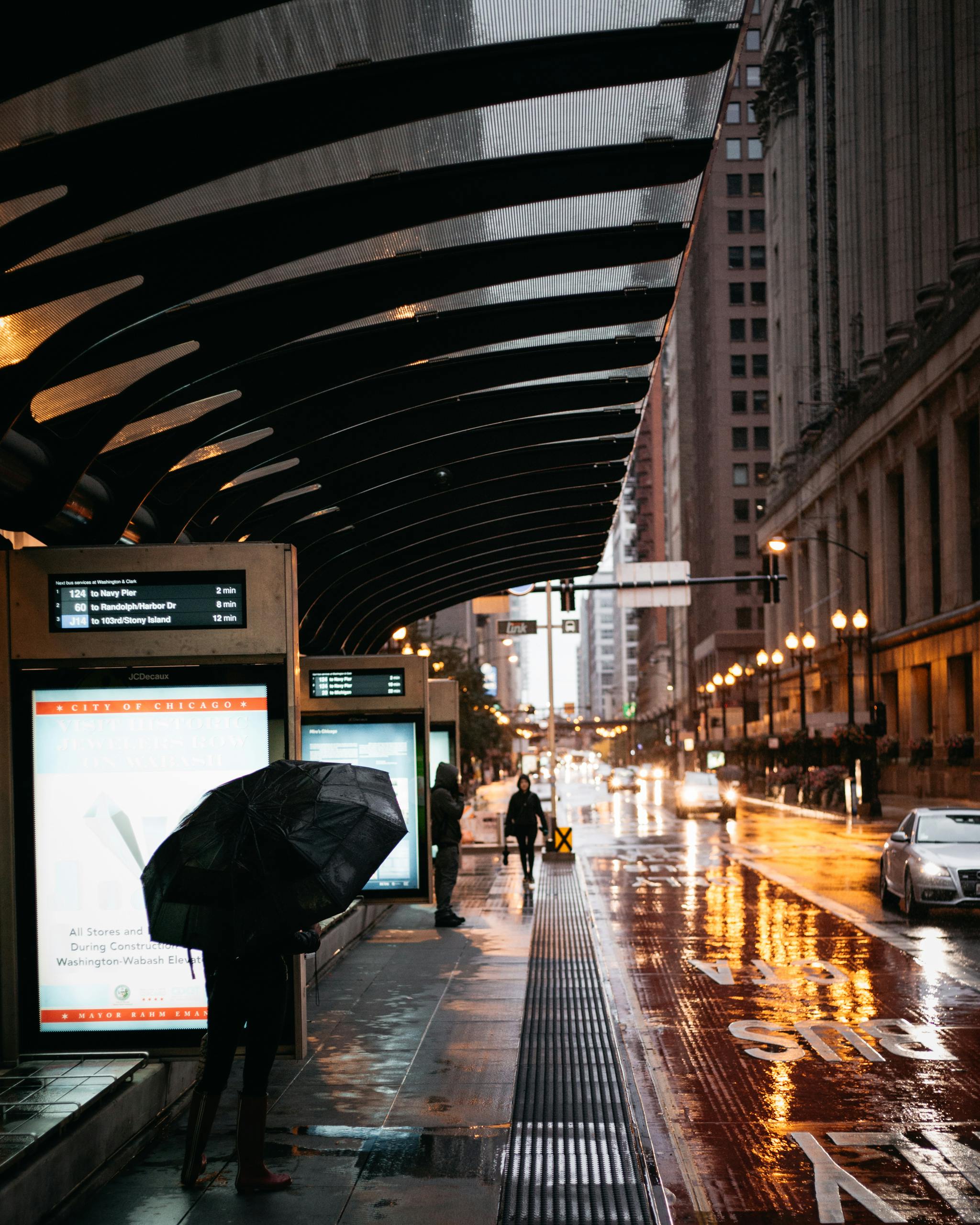 A rainy day in the city featuring people with umbrellas and reflective wet streets.