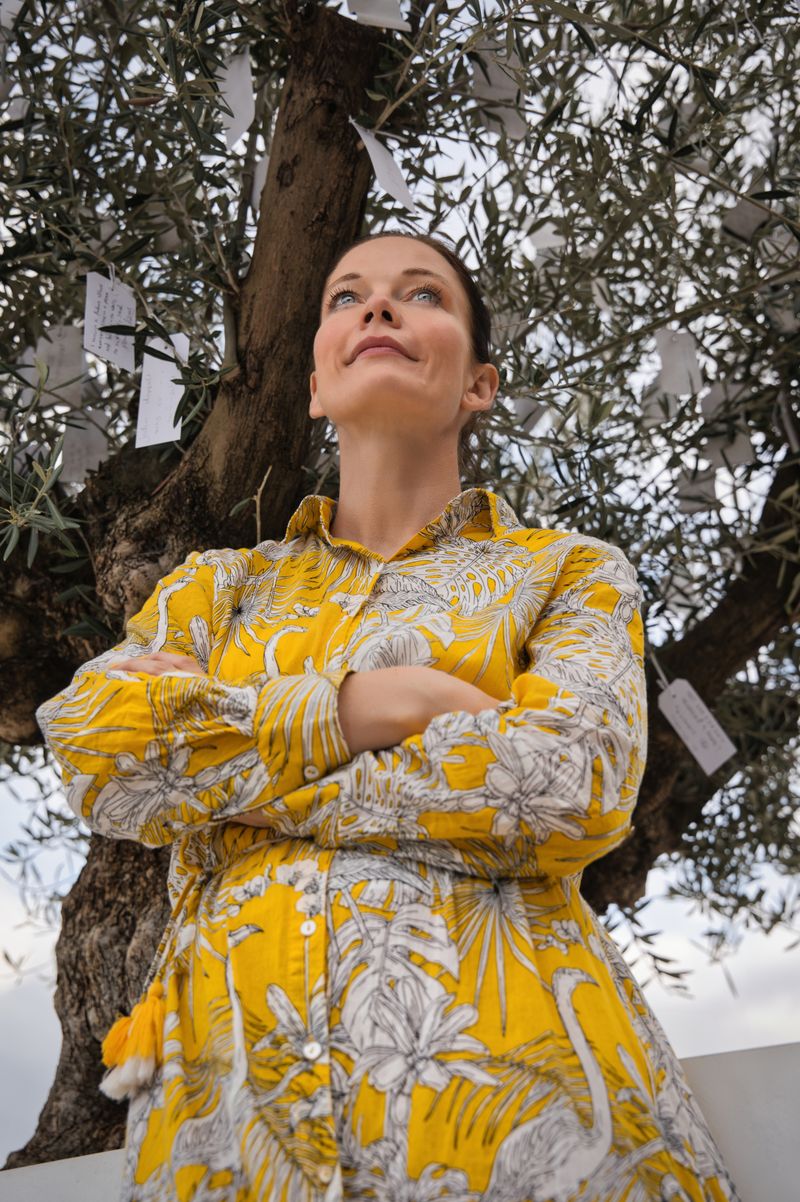 Woman in a yellow print dress beneath an olive tree — photo by Travel with Lenses on Pexels