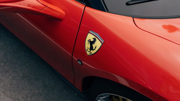 Detailed view of a sleek red sports car showcasing its iconic logo on the body panel.