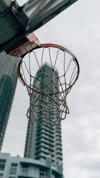 Basketball hoop against city skyscrapers, urban street sports scene.