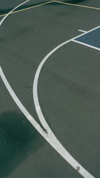 Abstract view of basketball court with white lines and green surface capturing simplicity and sport essence.