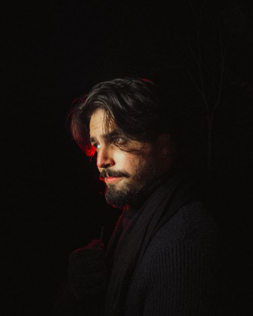 Free Dramatic portrait of a bearded man illuminated by red light in a dark setting. Stock Photo