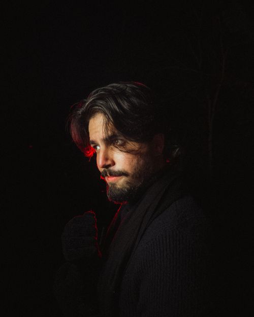 Free Dramatic portrait of a man under red lighting at night, evoking mystery and intrigue. Stock Photo