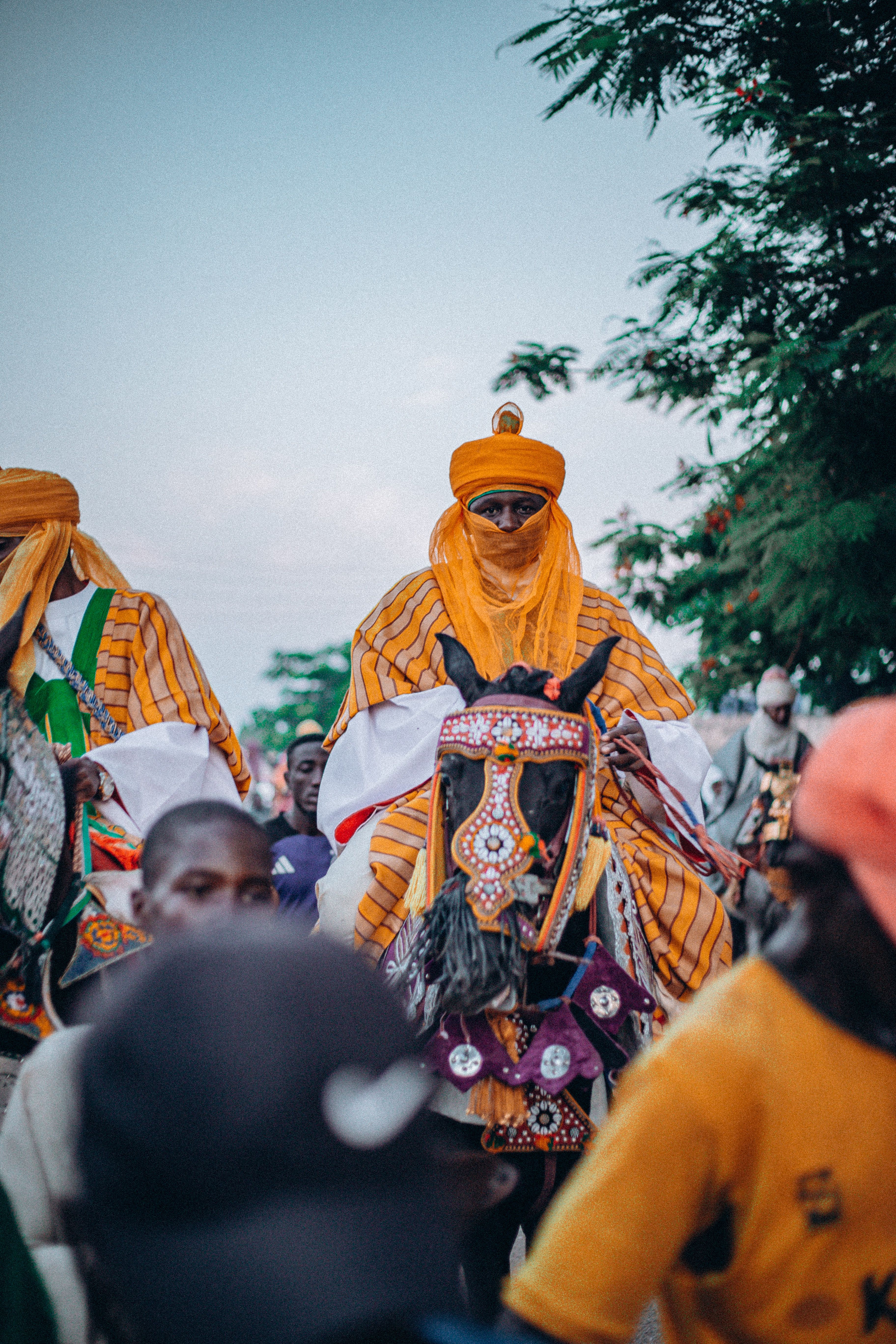 Vibrant traditional parade with ornately dressed men on horses, showcasing cultural heritage.